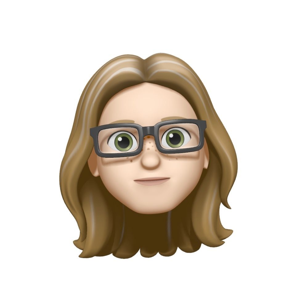 A cartoon avatar of a person with long brown hair and large green eyes. The avatar is wearing dark-framed glasses and has a light skin tone with freckles. The expression is pleasant, against a plain white background.